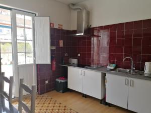 a kitchen with white cabinets and red tiles at Hostel Rossio Alcobaça in Alcobaça