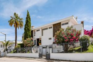 a white house with a fence and palm trees at Deluxe 4BDR House W/ Pool by LovelyStay in Portimão +53 photos