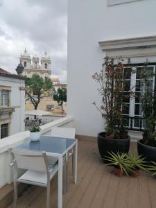 une table et des chaises blanches sur un balcon avec des plantes dans l'établissement Hostel Rossio Alcobaça, à Alcobaça