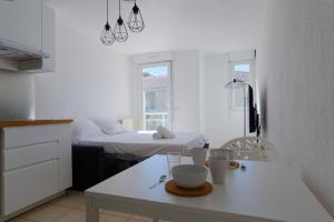 Cette chambre blanche comprend un lit et une table blanche. dans l'établissement Studio avec balcon et garage, à Marseille