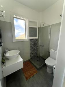 uma casa de banho com um lavatório, um WC e uma janela. em Seaside Studios em Arkasa