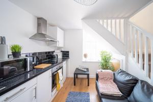 a kitchen with a black counter top and a couch at Bv Kirkstall Central 1 Bedroom Apt Free Private Parking in Leeds