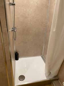 a shower with a glass door with a drain in it at EDI b&b in Edinburgh