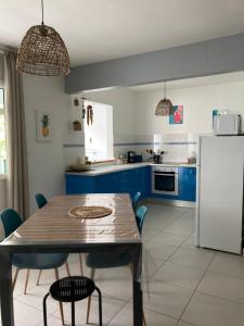 a kitchen with blue cabinets and a table and a refrigerator at Le Toutapied , Sainte-Anne, appartement en plein centre in Sainte-Anne