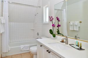 a white bathroom with a sink and a toilet and a tub at Wine Valley Inn in Solvang