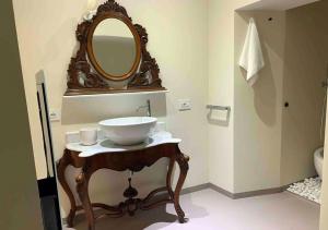La salle de bains est pourvue d'un lavabo et d'un miroir sur une table. dans l'établissement Junior suite, à Parme
