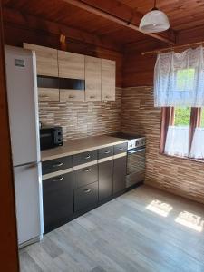 kuchnia z szafkami ze stali nierdzewnej i białą lodówką w obiekcie Dar Lasu w mieście Narty