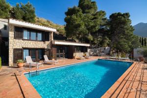 a villa with a swimming pool in front of a house at Stunning seaview villa in Altavilla Milicia