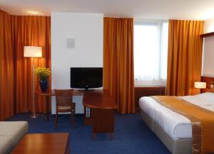 a hotel room with a bed and a desk with a television at Garni Hotel Azul in Kranj