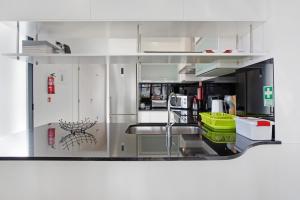 a kitchen with white cabinets and a stainless steel refrigerator at Recanto Dourado in Porto Santo