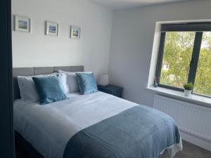 um quarto com uma cama com almofadas azuis e uma janela em Lux Lisburn Road, Belfast em Belfast
