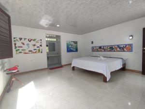 a bedroom with a bed and paintings on the walls at Isla Grande Eco-Hostal in Isla Grande