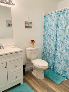 a bathroom with a toilet and a blue shower curtain at Peace On The Beach House in Panama City Beach +24 photos