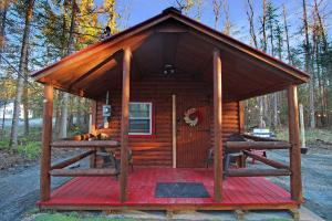 a cabin in the woods with a red deck at Travelers Haven in Whitefield