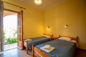 two beds in a room with a window at Tzoras‌ ‌Apartments‌ ‌Roda‌ ‌Corfu‌ in Litherés