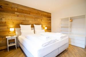 um quarto com uma cama branca e uma parede de madeira em Schiefer Suite Hotel & Apartments em Goslar