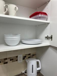 uma cozinha com pratos brancos e tigelas numa prateleira em Spacious room with TV, Wi-Fi, Netflix, Parking em Edmonton