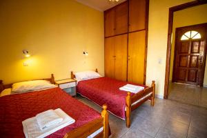 a bedroom with two beds with red sheets at Tzoras‌ ‌Apartments‌ ‌Roda‌ ‌Corfu‌ in Litherés