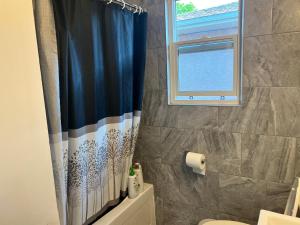 a bathroom with a shower curtain and a window at Spacious room with TV, Wi-Fi, Netflix, Parking in Edmonton