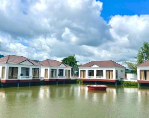a row of houses on a river with a boat at Rồng Vàng Resort in Tri Tôn