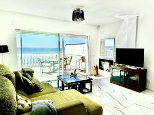 sala de estar con sofá y vistas al océano en Beachfront apartment with pleasant views of the sea and the historic lighthouse., en Mijas Costa