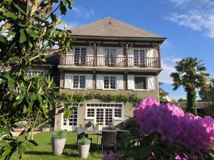 a large house with a balcony and purple flowers at Les Hortensias in Espoey