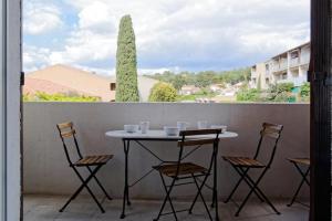 a table and chairs on a balcony with a tree at Studio Cosy Aigues Marines in Saint-Cyr-sur-Mer