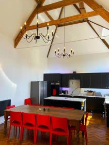 uma cozinha com uma mesa de madeira e cadeiras vermelhas em Bodham School Halls - 5 Bedrooms em Bodham