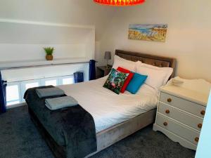 a bedroom with a bed with colorful pillows and a dresser at Bodham School Halls - 5 Bedrooms in Bodham