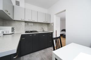 a kitchen with black and white cabinets and a table at Silver by OneApartments in Sopot