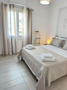 um quarto branco com uma cama grande e toalhas em Leo House Kea em Korissia