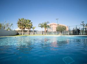 a swimming pool with blue water in front of a fence at SibsSanlucar McVILLA - Atico con Piscina in Sanlúcar de Barrameda