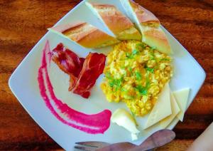 un plato de desayuno con huevos tocino y queso en Café des Arts Gili Air, en Gili Air
