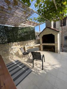 eine Terrasse mit einem Tisch, Stühlen und einem Kamin in der Unterkunft Studio Apartment Klaric in Vis