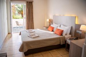 ein Hotelzimmer mit einem großen Bett mit orangefarbenen Kissen in der Unterkunft Kalloni Bay in Skala Kallonis