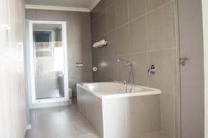 ein Badezimmer mit einer weißen Badewanne und einer Dusche in der Unterkunft Bay View Resort Hotel Namibia in Swakopmund