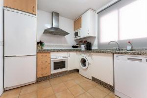 een keuken met witte kasten en een wasmachine en droger bij Apartamento Postal in Fuengirola