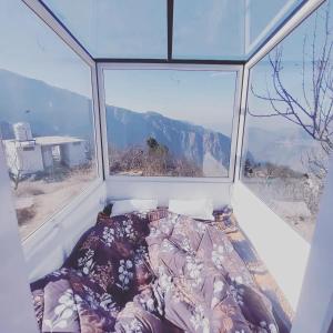 Cama en habitación con ventana grande en Stargazing Glass Lodge Himachal Pradesh Thachi en Mandi