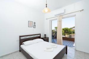 a white bedroom with a bed and a balcony at Omnia Maisonette by A&D Properties in Porto Rafti