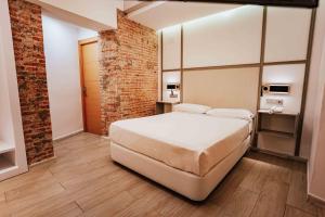 - une chambre avec un lit et un mur en briques dans l'établissement Atenas Granada, à Grenade