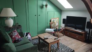 a living room with a couch and a tv at Calme et confort à la campagne en Bourgogne vinicole, 