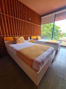 a bedroom with two beds and a large window at Hotel Momotus in Tuxtla Gutiérrez