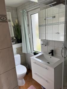 ein weißes Bad mit einem WC und einem Waschbecken in der Unterkunft Bungalow in Gager