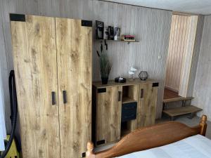 1 dormitorio con armario de madera junto a la cama en Bungalow, en Gager