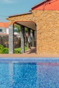 a swimming pool with a stone wall next to a building at Aroeira Pool House by Lisbon-Coast vacation in Charneca