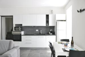 una cocina con armarios blancos y una mesa blanca con mesa en Al Pontile - by My Home In Como, en Argegno