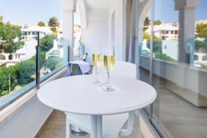 two glasses of champagne on a white table on a balcony at Mar Hotels Alcanada in Port d'Alcudia