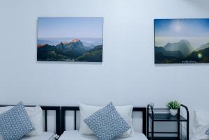 een woonkamer met een bank en twee foto's van de bergen bij 24 Poshtel Chiangmai in Chiang Mai