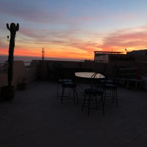 a table and chairs on a rooftop with a sunset at Surf Lovers Morocco in Agadir