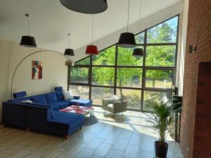 a living room with a blue couch and large windows at Instytut Wypoczynku in Sulęczyno +25 photos